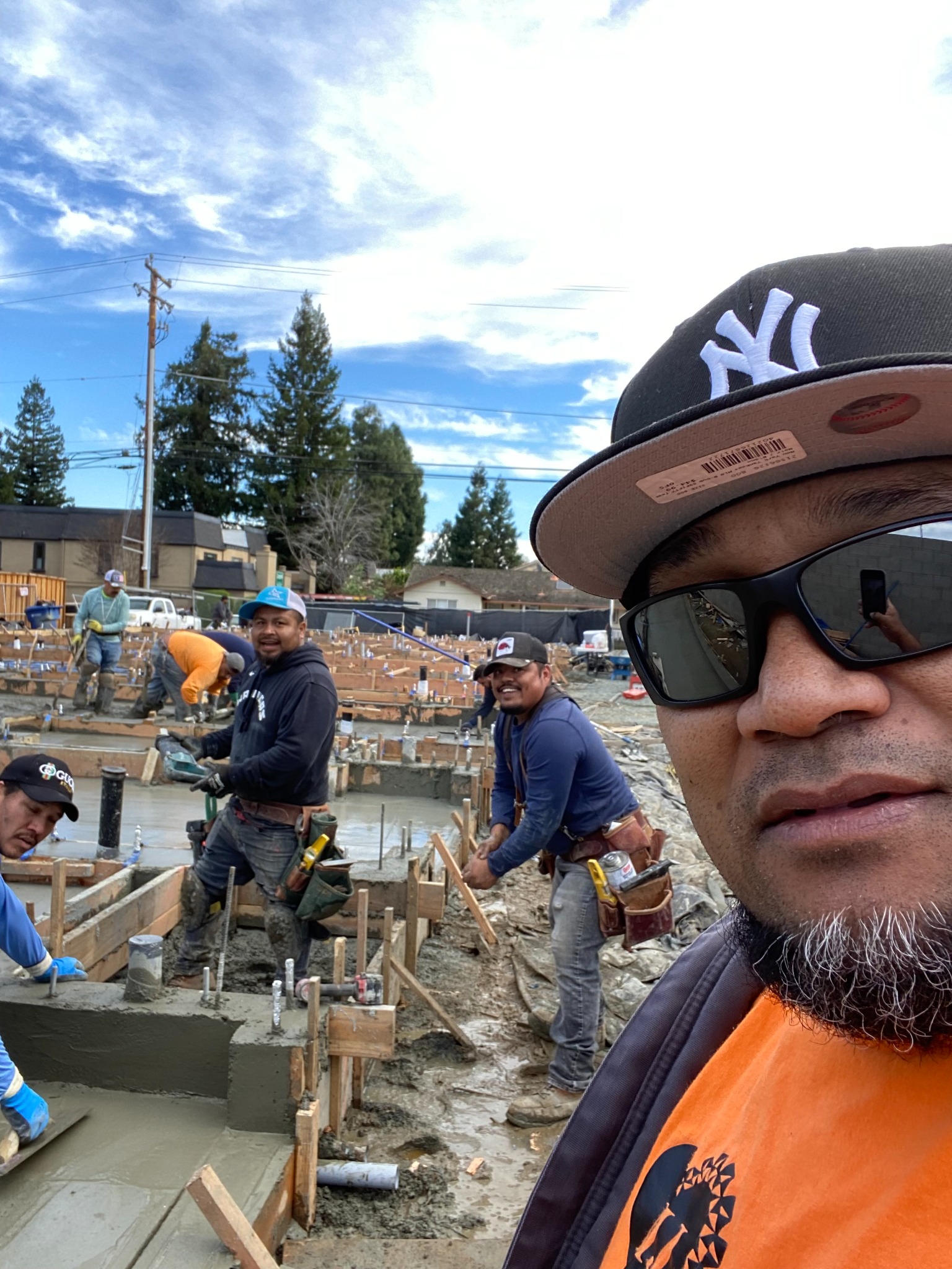 Workers smoothing concrete within timber forms at a construction site, with a person in the foreground.