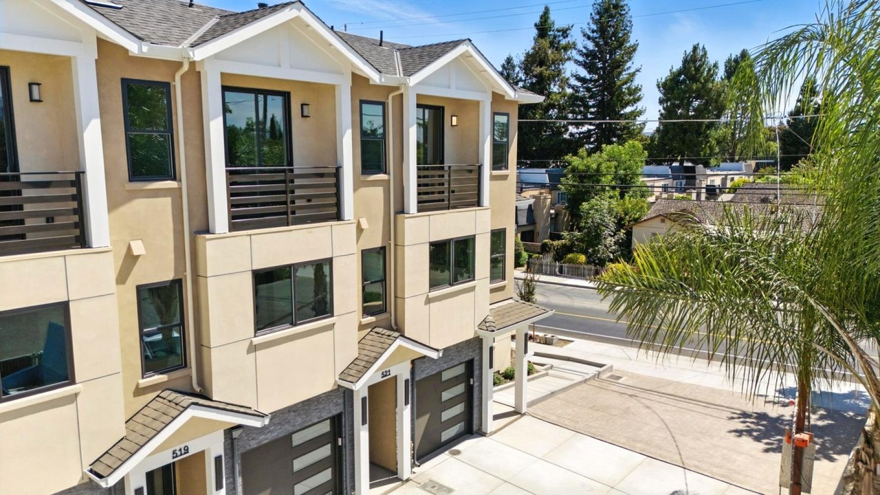 Residential building with balconies, cream walls, white trim and dark garage doors.